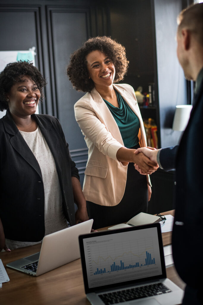 two people (media execution partners) smiling shaking hands, with one in the background smiling as well.
