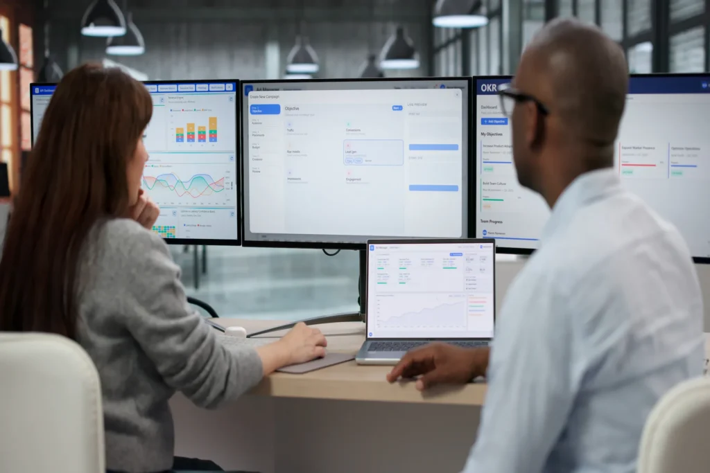 Digital marketing team using a demand side platform dashboard to manage DSP advertising campaigns with analytics and performance tracking on multiple screens.
